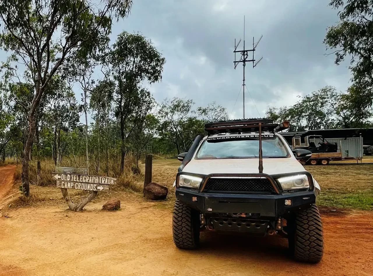 A Hilux at the start of the Old Telegraph Track, a signpost pointing to the track and camp grounds.