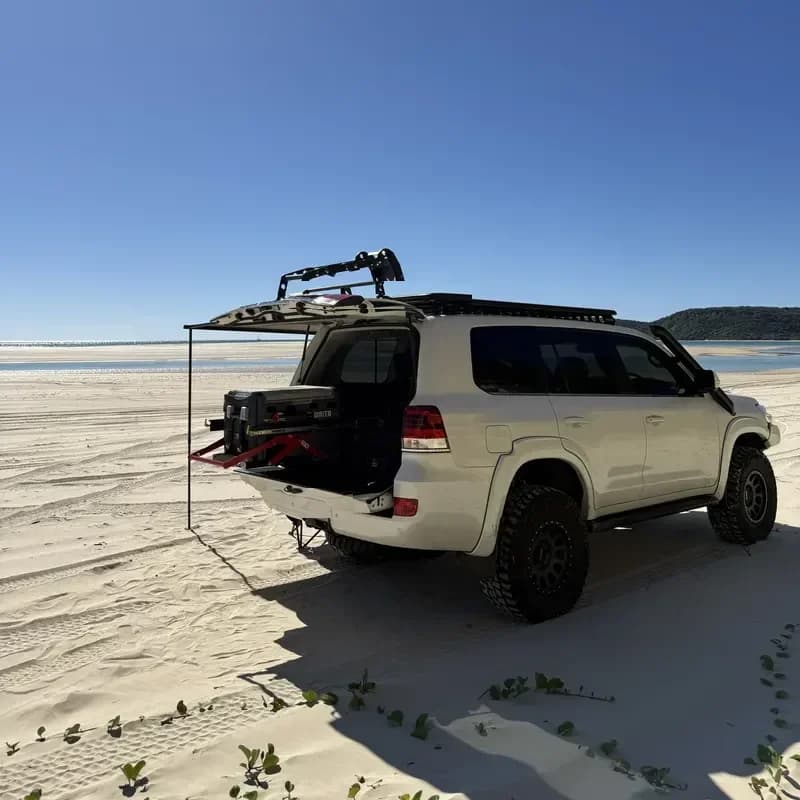 A 200 Series on the sand, the rear open and the awning rigged.
