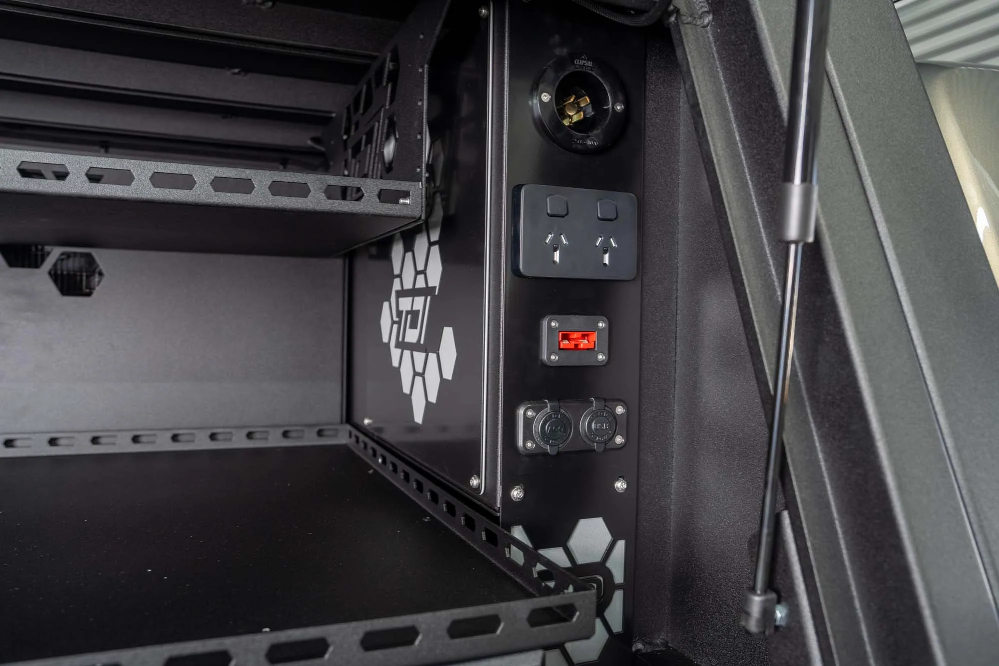 Inside a TDI canopy: a power panel with 240V outlets, an Anderson plug and USB ports beside the shelving.