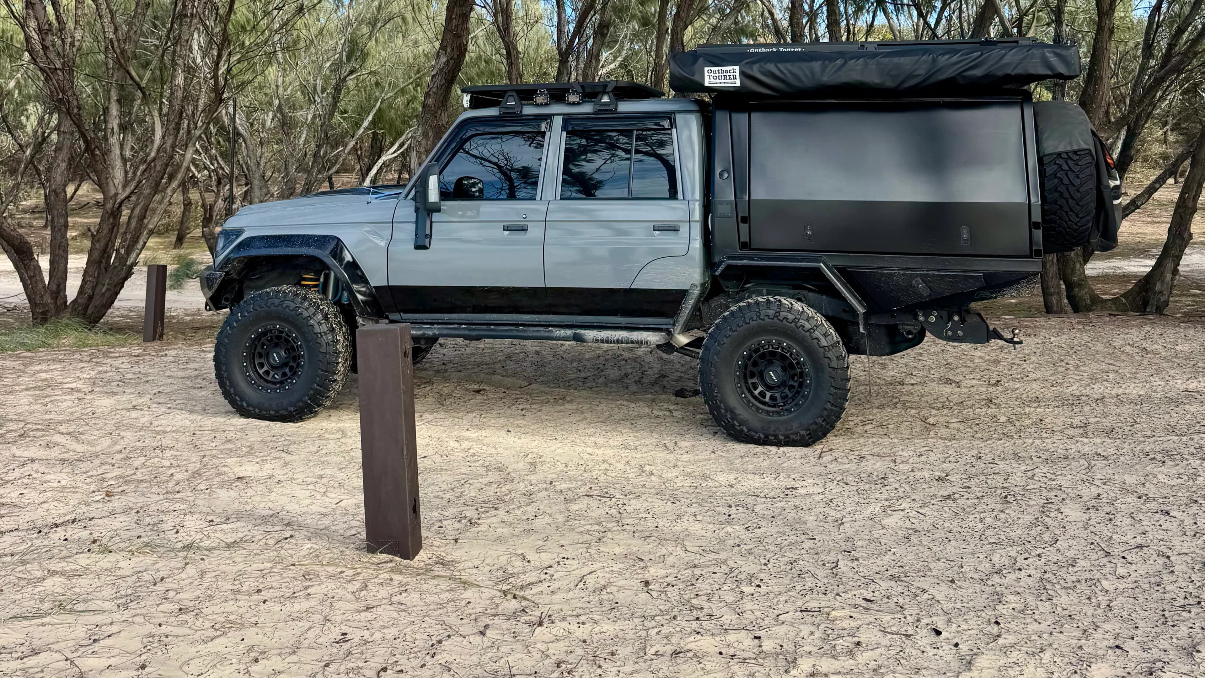 Drewsy's 79 side on at a sandy bush track, canopy and roof rack in view.