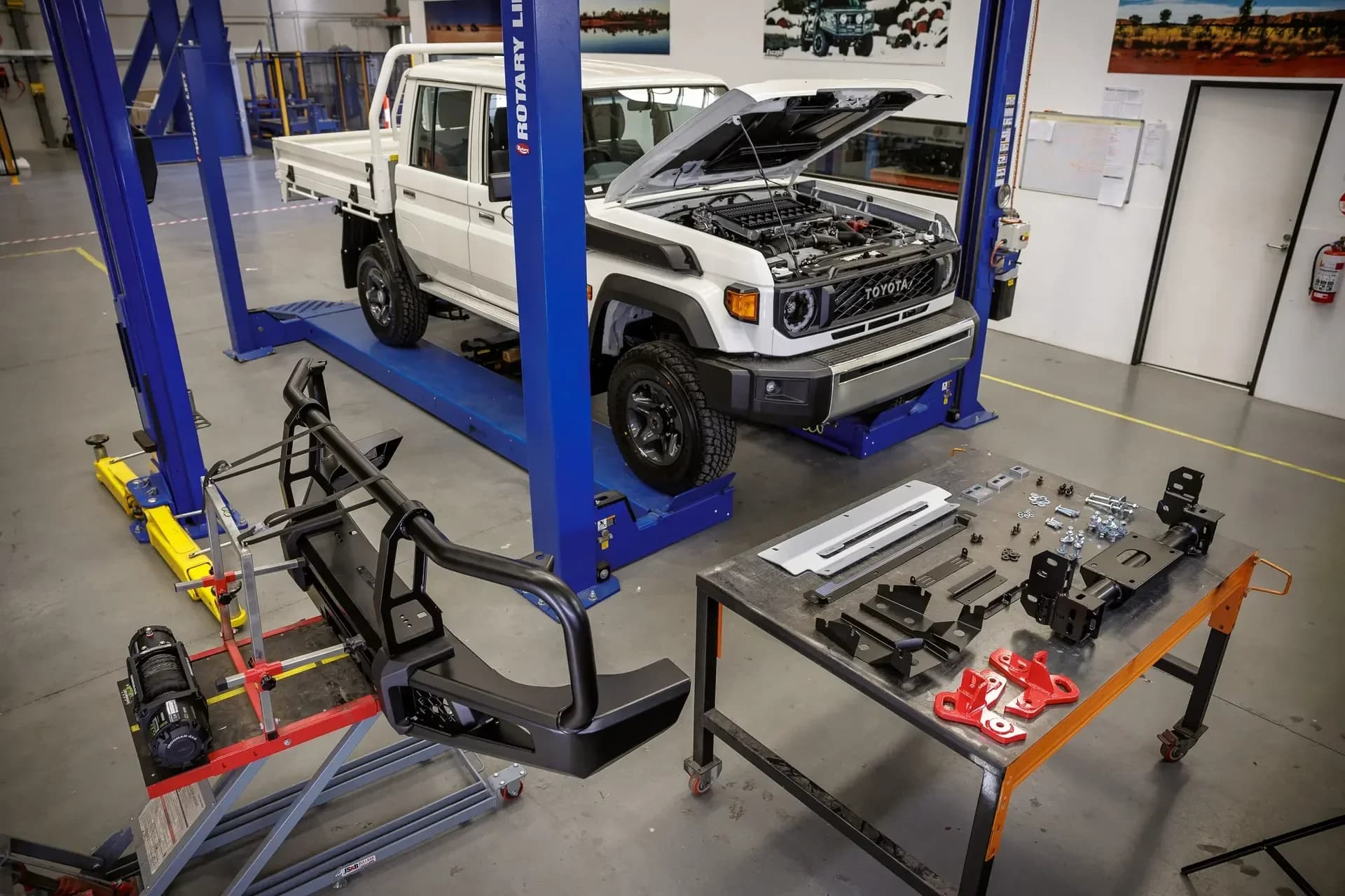 A 79 Series on a workshop hoist, bar work and fittings laid out on the bench.